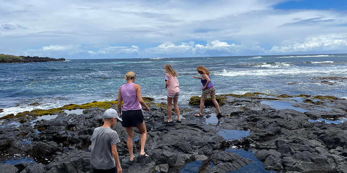 A group of people exploring a black sand beach in Hawaii