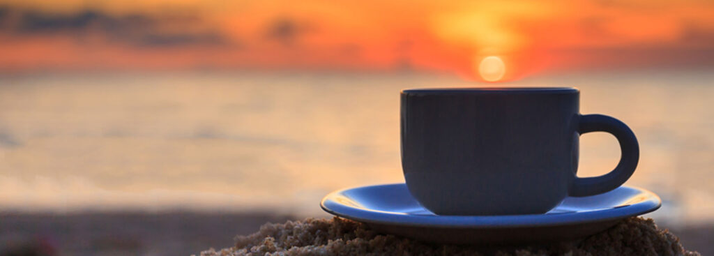 cup of coffee on the beach over looking the sunset